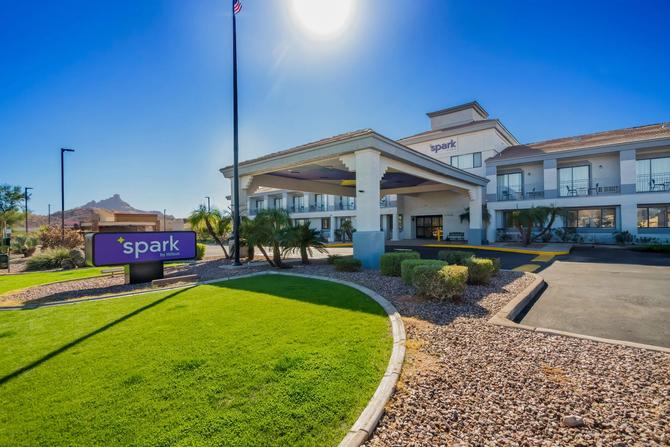 Exterior of a Spark by Hilton hotel with a green lawn on a blue sky, sunny day