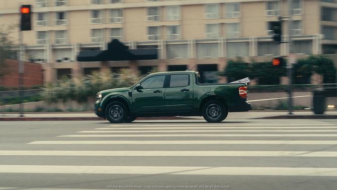 A green Ford Maverick driving on a road