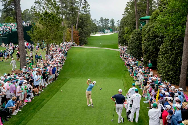 A golfer hitting the golf ball with fans watching
