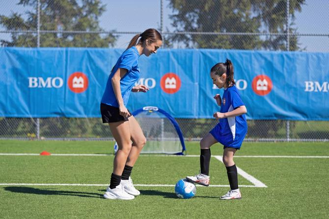 An older soccer player coaching a younger soccer player on a soccer field