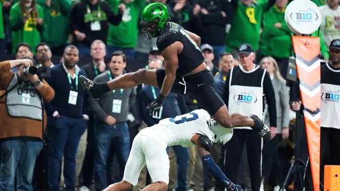 Oregon football player leaps over Penn State football player during 2024 Big Ten Championship.