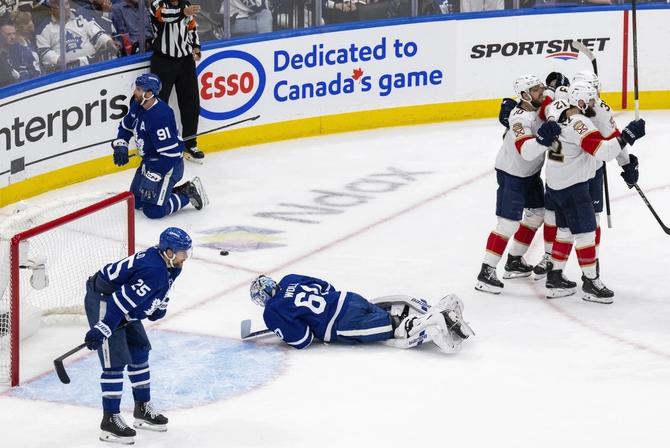 Three Florida Panthers players celebrate a goal, while Toronto Maple Leafs goalie Joseph Woll, forward John Tavares, and defenseman Brandon Carlo react.