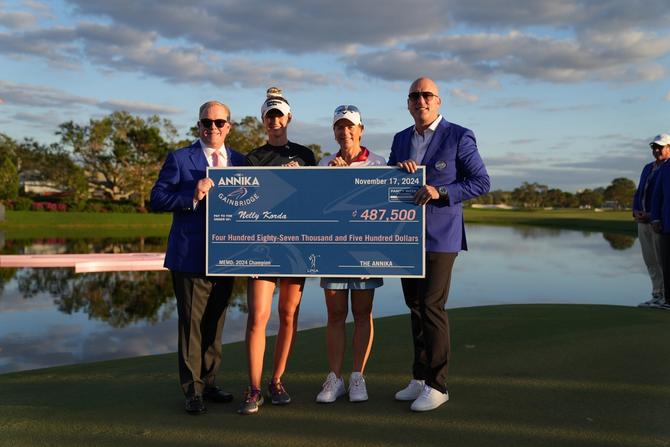 Nelly Korda holding up a check on the golf course with Annika Sorenstam and two men