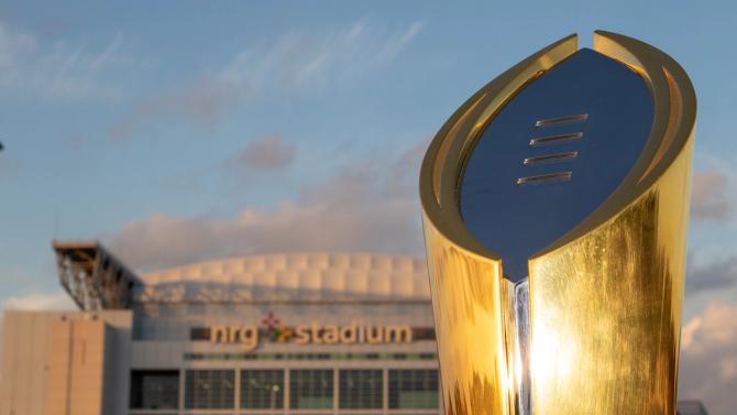 The College Football Playoff national championship trophy in the foreground, with Houston’s NRG Stadium in the background.
