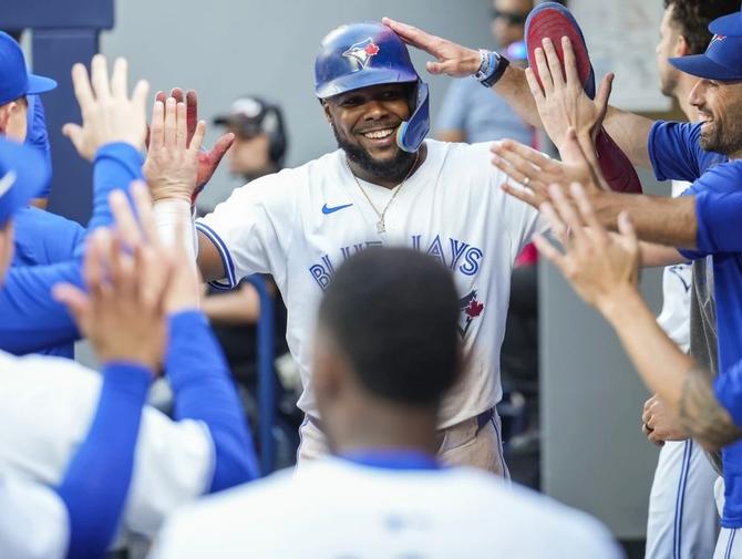 Toronto Blue Jay Vladdy Guerrero Jr. high fives his teammates in the dugout after hitting a home run.