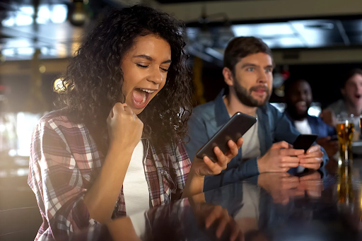 A woman celebrates while looking at her phone screen.
