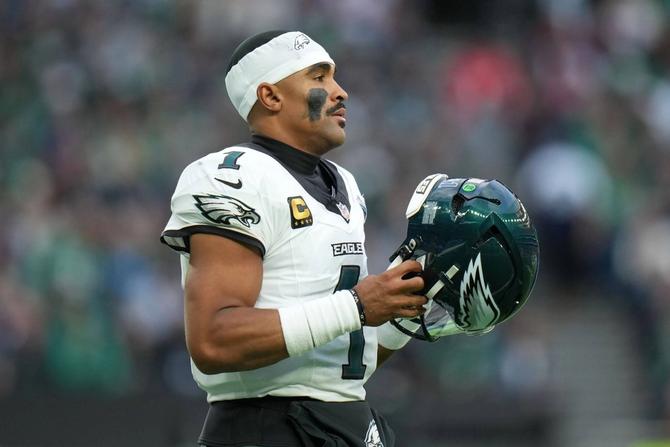Philadelphia Eagles QB Jalen Hurts holds his helmet in his hands.