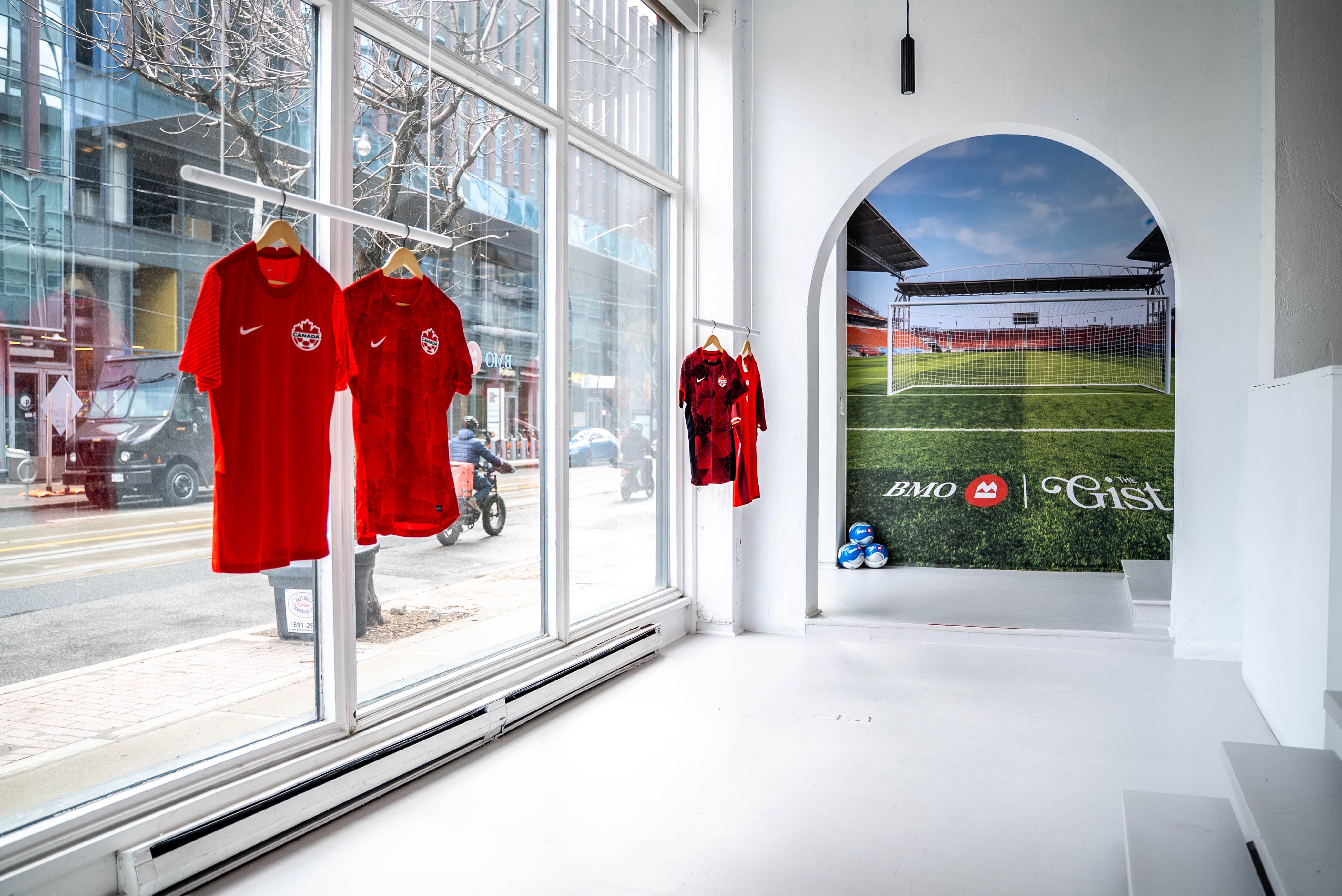 Team Canada jerseys hang in the window of an activation space.