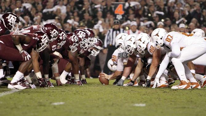 Texas’ and Texas A&M’s football teams face off at the line of scrimmage during a game.
