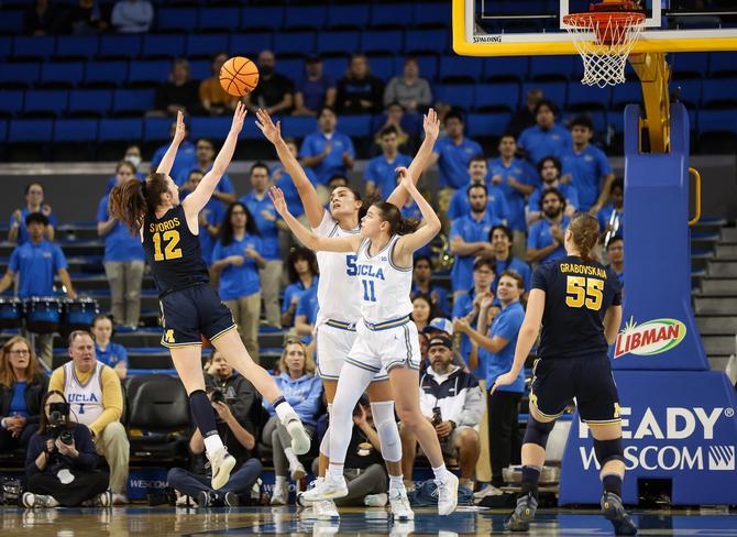 Michigan Wolverine Syla Swords shoots the ball over two UCLA players.