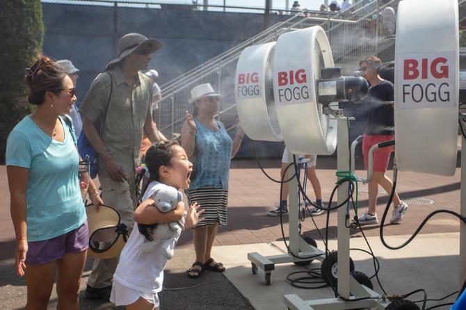 The delight shows on the face of a young fan as spectators cool off in water spray during a sweltering day at the US Open Fan Week and qualifying tournament in preparation for next week's US Open Tennis Championship 2022 at the USTA National Tennis Centre on August 25th, 2022 in Flushing, Queens, New York City.