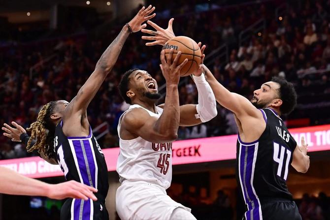 Cleveland Cavalier Donovan Mitchell drives to the basket against two Sacramento Kings defenders.