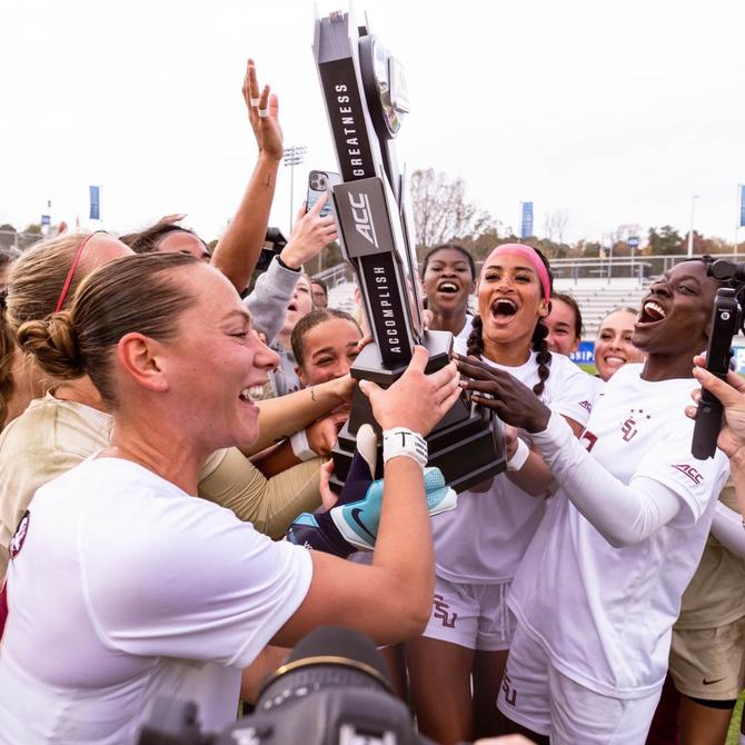 Florida State soccer players hoisting a trophy after winning the ACC Tournament for the fifth season in a row.