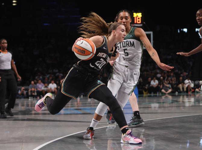 Sabrina Ionescu dribbling the basketball against defenders