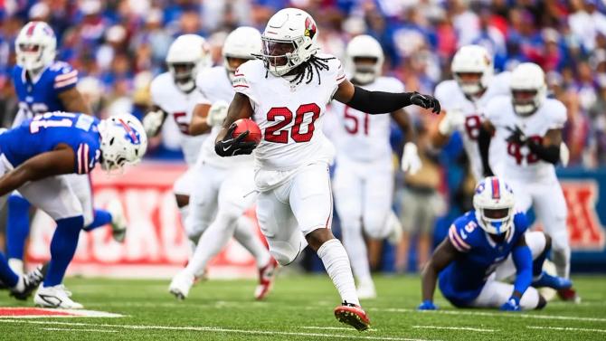 Arizona Cardinals return specialist DeeJay Dallas runs the ball while evading tackles from Buffalo Bills players.
