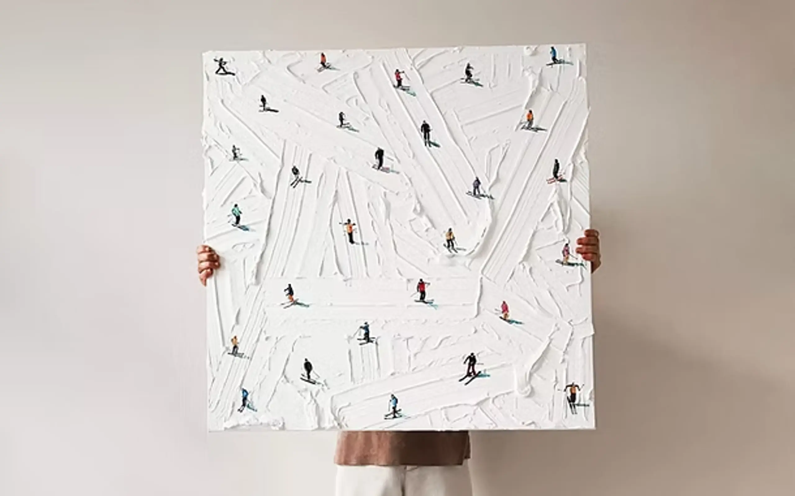 A figure holds a Werner Bronkhorst painting depicting skiers. 