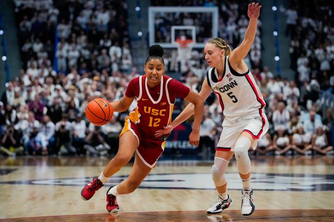JuJu Watkins #12 of the USC Trojans is defended by Paige Bueckers #5 of the Connecticut Huskies during the second half of an NCAA women's basketball game at the XL Center on December 21, 2024 in Hartford, Connecticut.