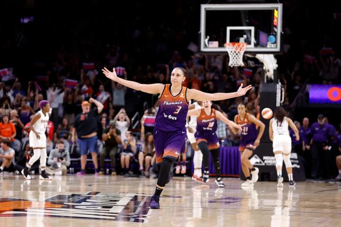 Diana Taurasi runs up the court with her arms outstretched in celebration.