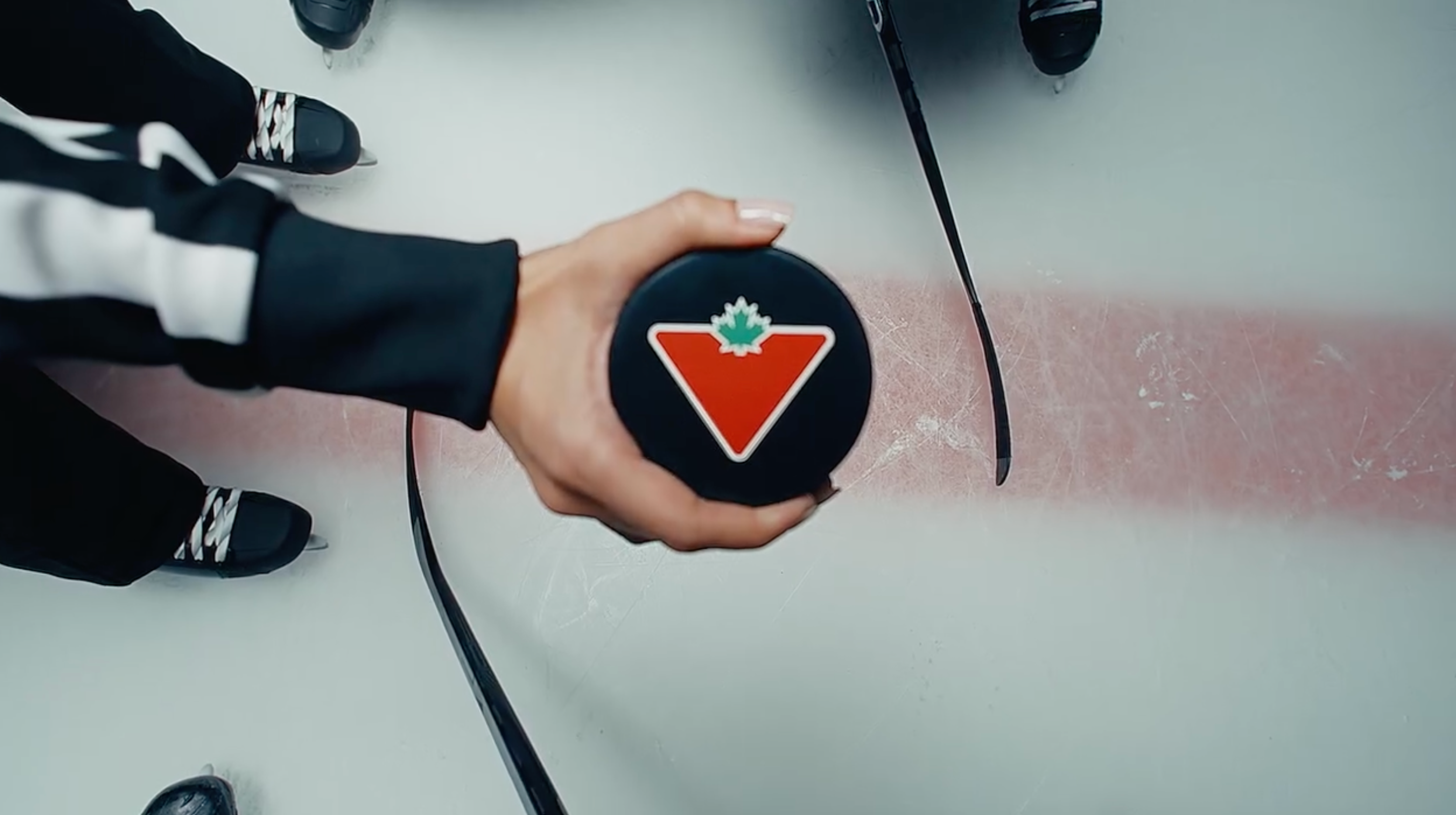 A Canadian tire logo is pictured on a hockey puck that is being held by an official.