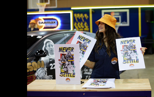 A CarMax representative showcases posters at a WNBA event.