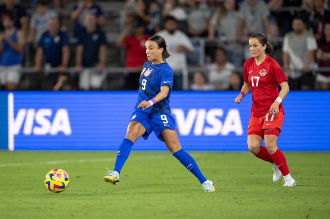 USWNT forward Mallory Swanson passes the ball away from CanWNT midfielder Jessie Fleming.