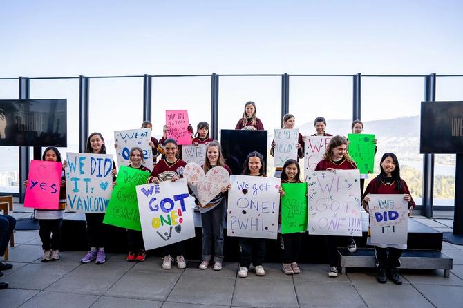 Members of one of Vancouver’s youth hockey teams pose with signs at a PWHL press conference announcing the city as the league’s newest expansion team.