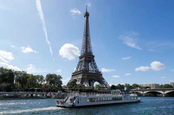 A boat floats past the Eiffel Tower on the Seine River.