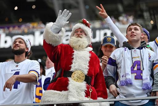 A Minnesota Vikings fan dressed up as Santa Claus waves to the crowd.