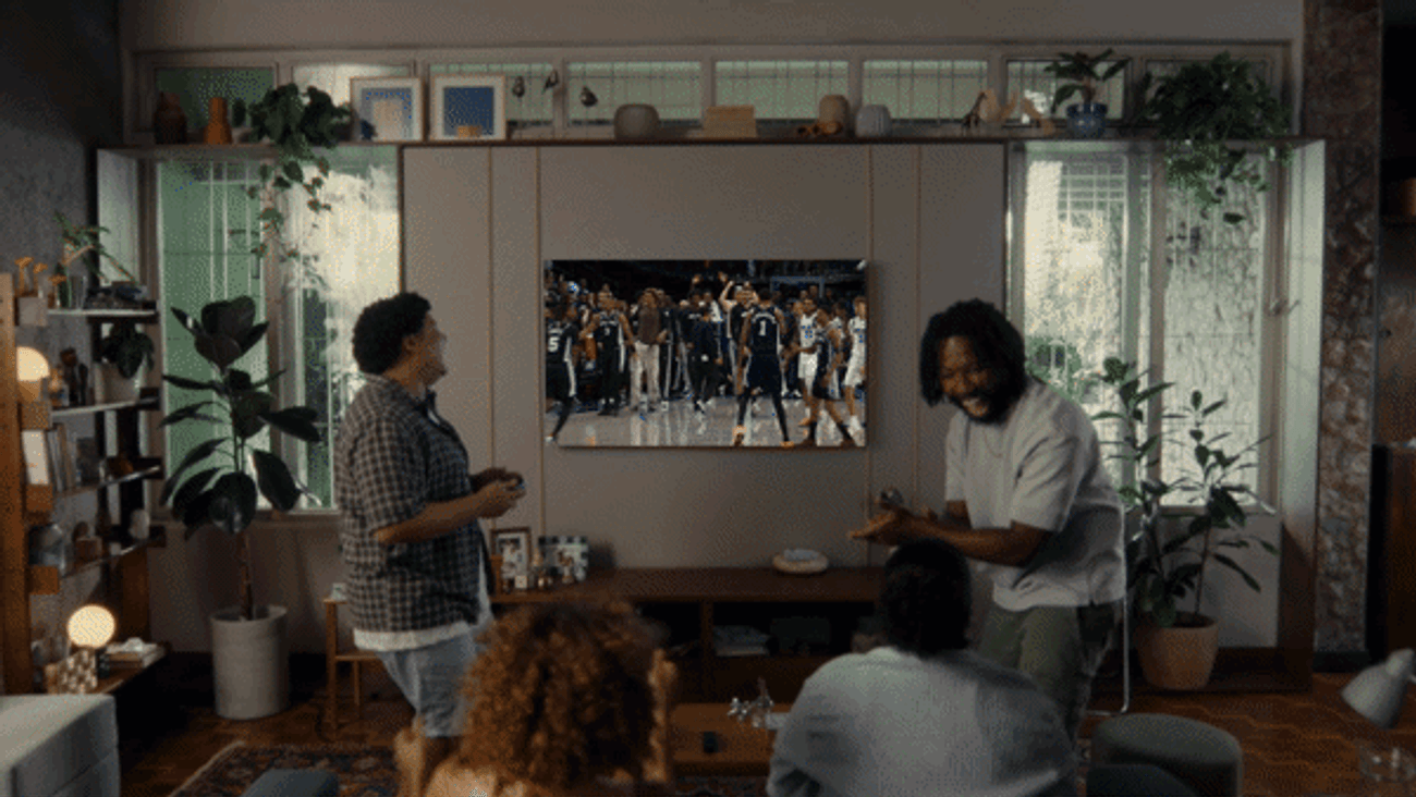 Zoom out from living room playing sports to doorstep with Amazon box Text reads 