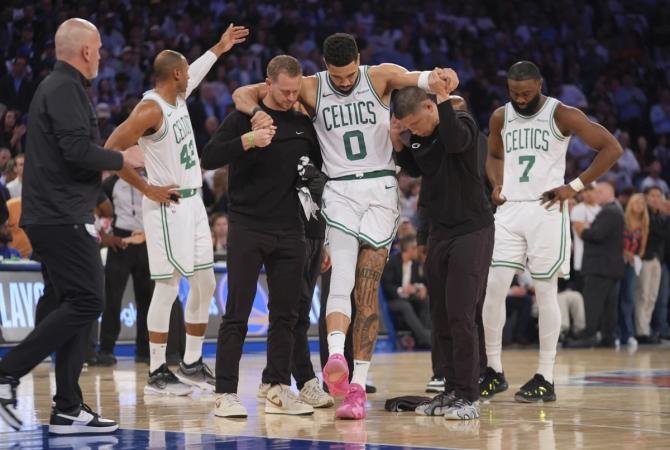 Boston Celtic Jayson Tatum is helped off the court by training staff.