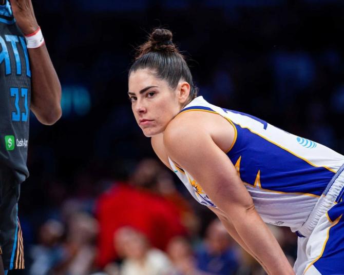 Kelsey Plum has her game face on while standing with her hands on her knees on the court.