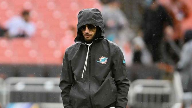 Miami Dolphins head coach Mike McDaniel walks up the sideline with his hood up and sunglasses on.