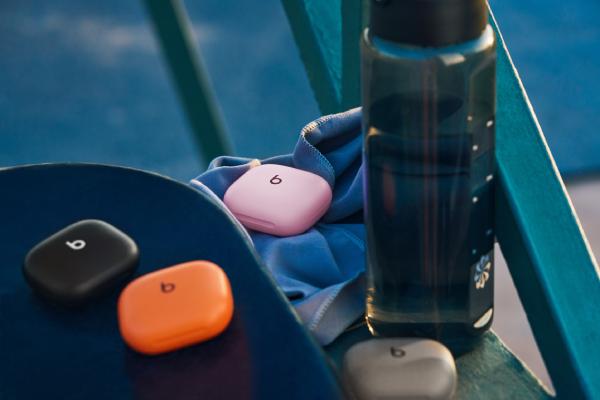 A collection of Powerbeats Fit on a bench next to a water bottle