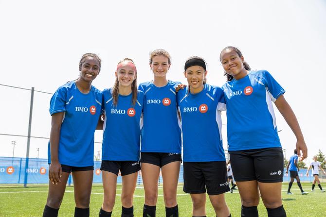 A group of soccer players smiling on the pitch