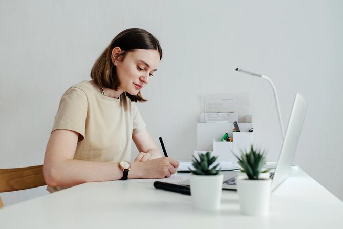 A person writing in a journal at a desk