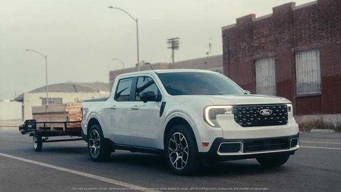 A white Ford Maverick pulling a cart filled with wood on a road