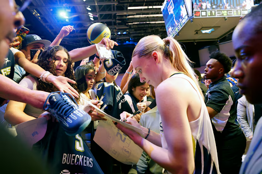Paige Bueckers signs a paper for a Dallas Wings fan.