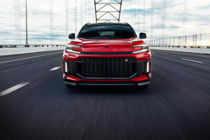 Front-facing view of a red Toyota RAV4 driving across a suspension bridge, highlighting its bold grille, sleek lighting, and sporty performance-focused design.
