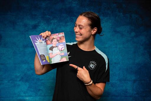 Gotham FC defender Lilly Reale poses with a copy of Changing the Game: A Playbook for Champions in Training.