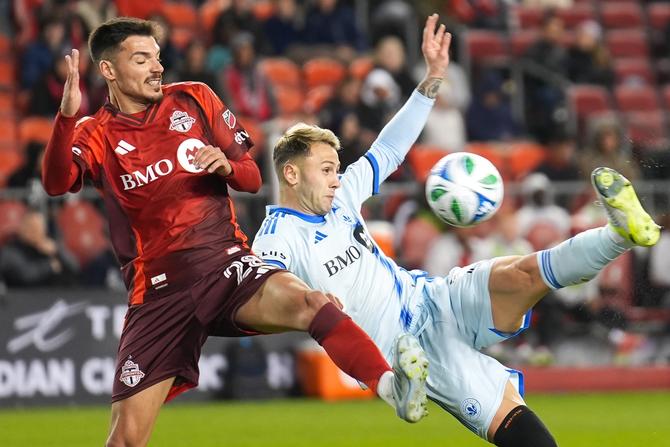 Two MLS soccer players fighting for position on a soccer ball on the field