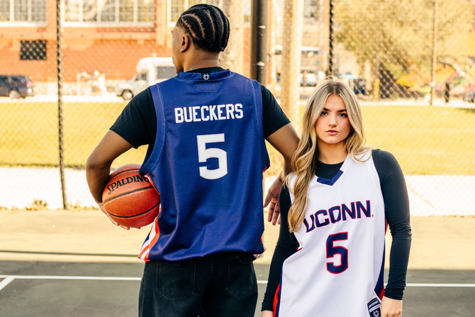 Two people modelling Paige Bueckers' basketball jersey in an outdoor court