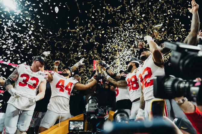 The Ohio State Buckeyes celebrate their national title win with the trophy as confetti falls.