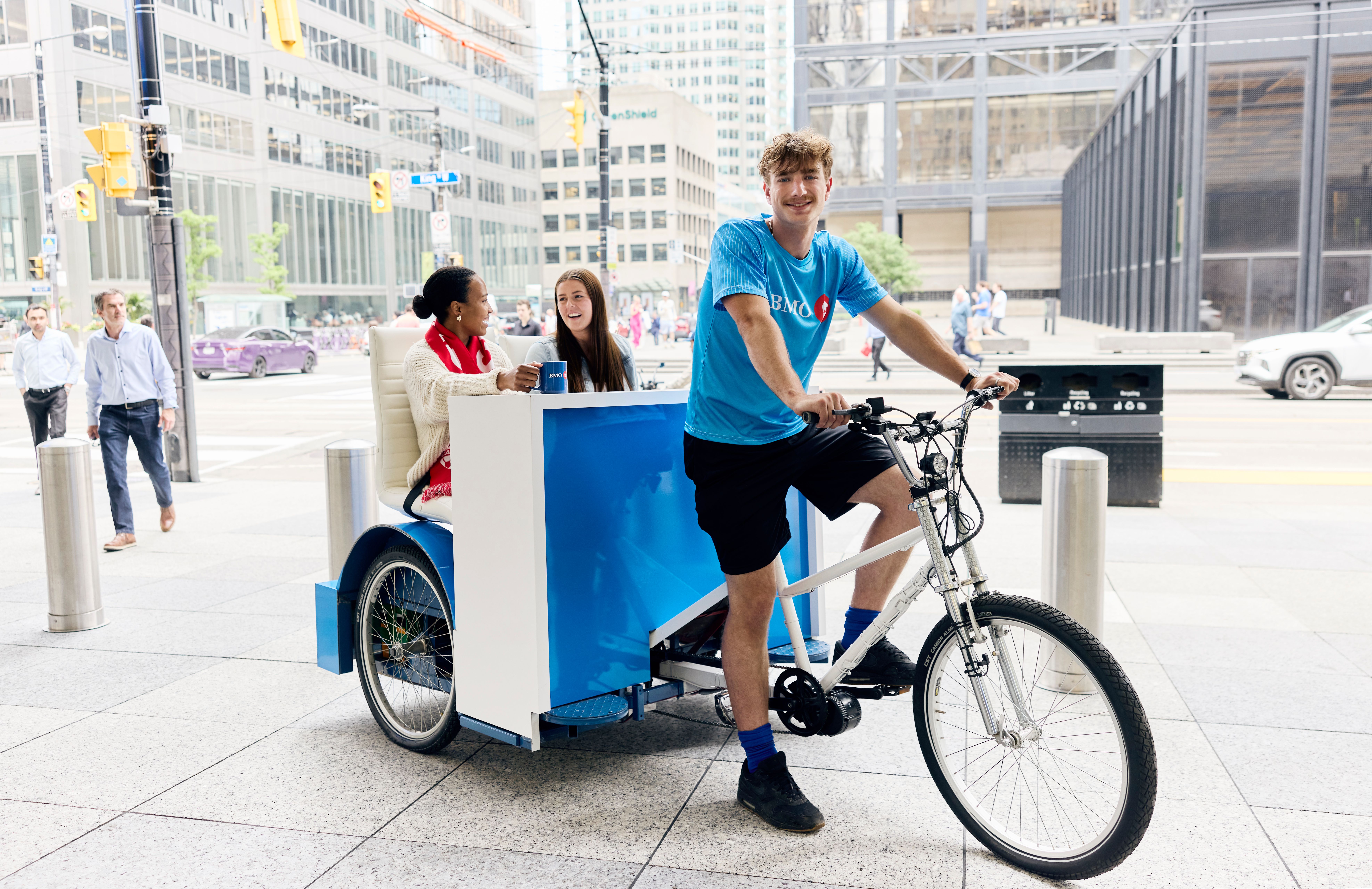 Two people riding a BMO sponsored rickshaw in downtown Toronto