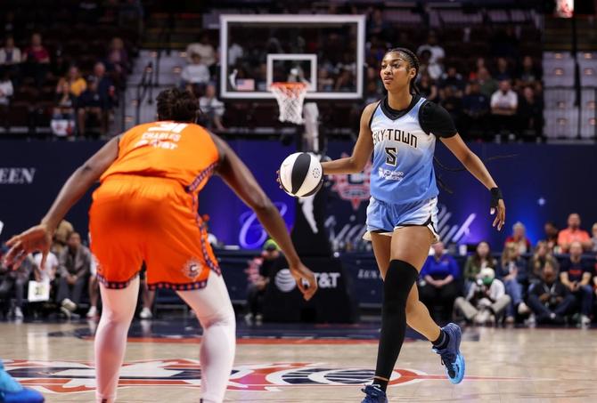 The Chicago Sky’s Angel Reese dribbles the ball up the court while being defended by the Connecticut Sun’s Tina Charles.