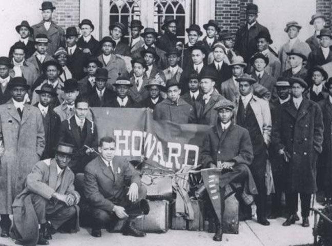 A group of Howard University students pose for a photo with a banner that says Howard.