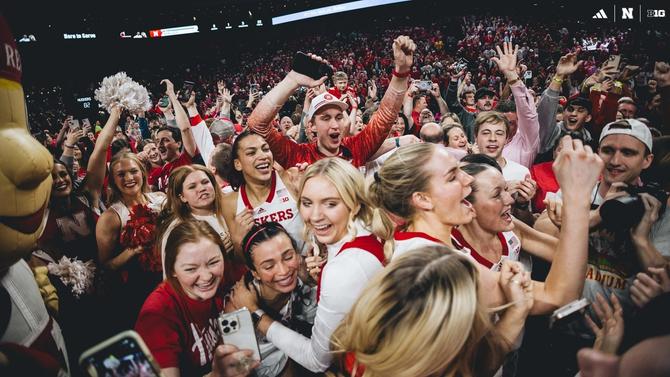 The Nebraska women’s basketball team celebrates with court-storming fans after upsetting No. 2 Iowa yesterday.