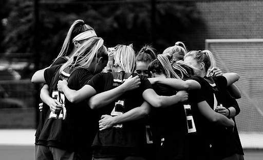 Women’s soccer players embrace during a game.