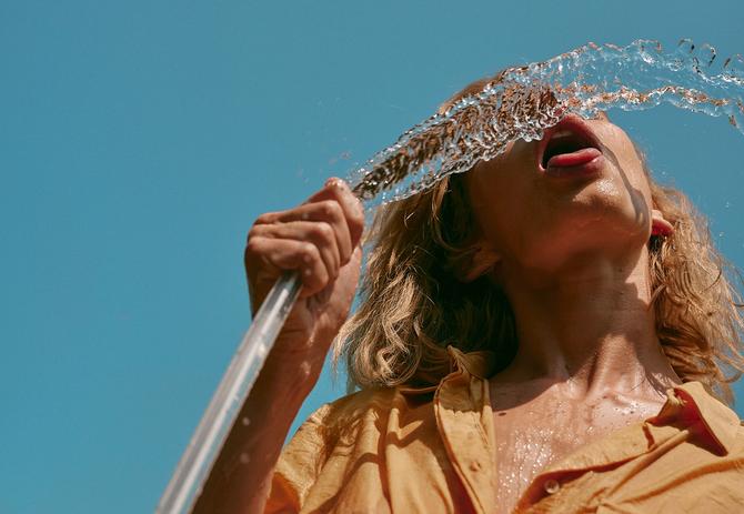A person drinking water from a hose