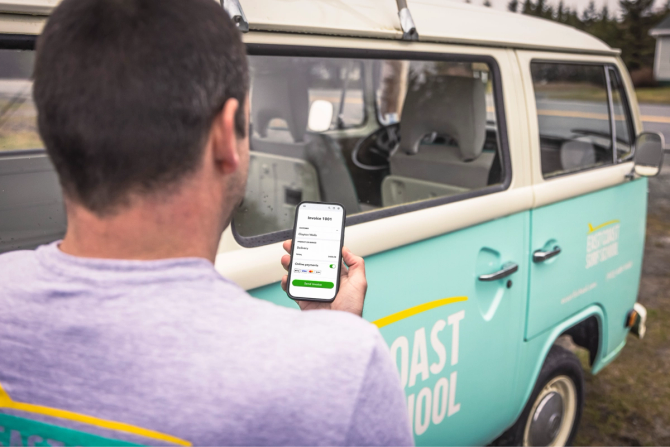 A man stands in front of his van holding his cellphone.