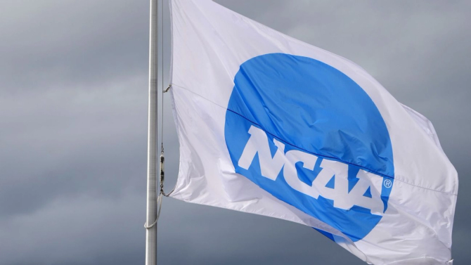 The blue NCAA logo on a white flag against the backdrop of a cloudy sky.